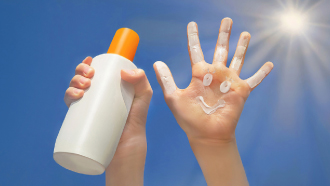 Mãos de pessoa ao sol, depois de ter aplicado protetor solar.